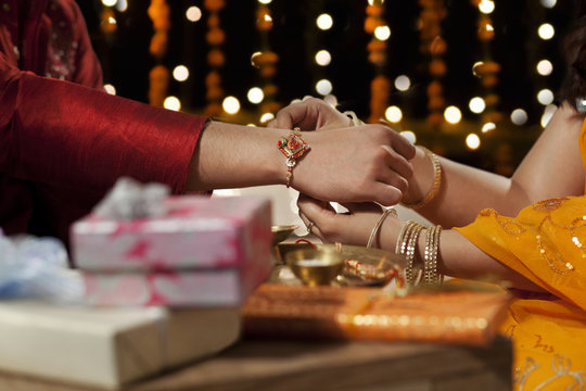 Close-up of a woman tying rakhi on her brother's hand