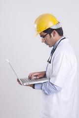 Side view of technician using laptop against gray background