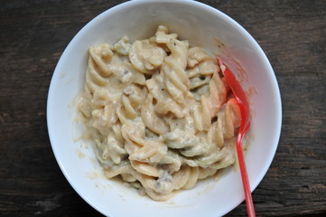 colored of macaroni in white bowl and red spoon on the wooden table.