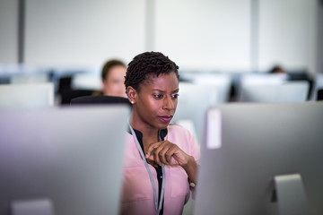 Businesswoman using computer in crowded office