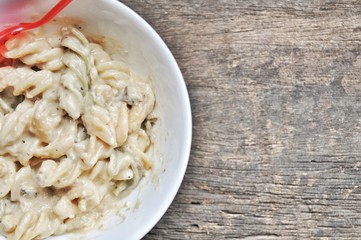 colored of macaroni in white bowl and red spoon on the wooden table.