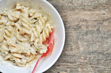 colored of macaroni in white bowl and red spoon on the wooden table.