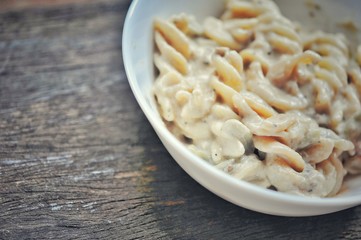 colored of macaroni in white bowl and red spoon on the wooden table.