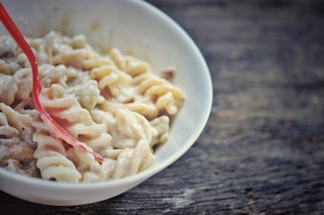 colored of macaroni in white bowl and red spoon on the wooden table.