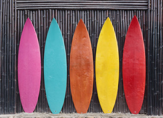 Colored surfboards leaning up against a wooden fence