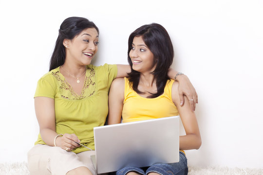Mother and daughter looking at each other while shopping online 