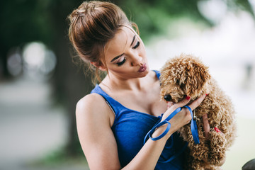 Portrait of beautiful young woman with her little red poodle puppy.