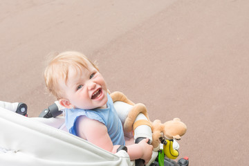the child sits in the stroller and smiling sweetly