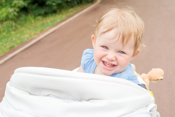 the child sits in the stroller and smiling sweetly