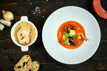 Homemade seafood soup with tomato sauce and coconut milk on an old wood tray