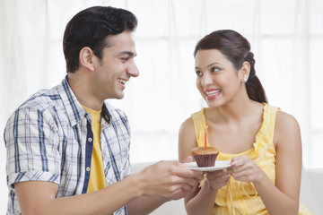 Young couple holding a plate with a cupcake
