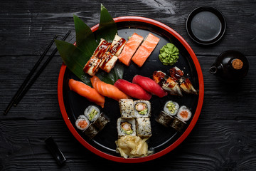 Japanese cuisine. Sushi set on a round plate over dark wooden background.
