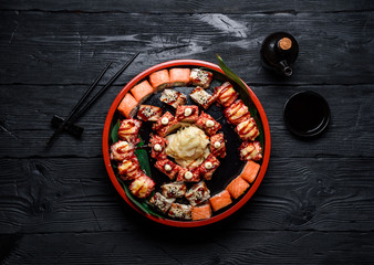 Japanese cuisine. Sushi set on a round plate over dark wooden background.