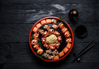 Japanese cuisine. Sushi set on a round plate over dark wooden background.