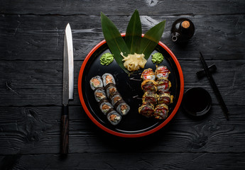 Japanese cuisine. Sushi set on a round plate over dark wooden background.