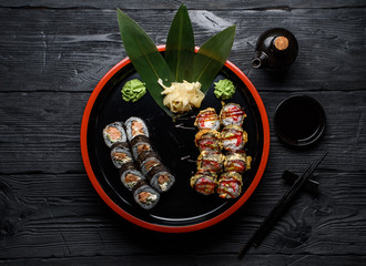 Japanese cuisine. Sushi set on a round plate over dark wooden background.