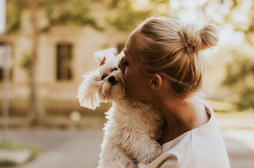 Portrait of young woman holding and kissing a maltese dog