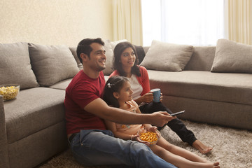 Family sitting on carpet watching television