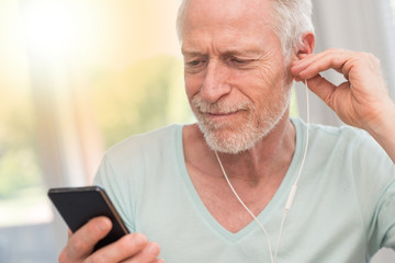 Portrait of mature man listening music with earphones, light effect