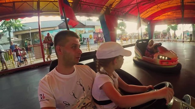 Father and daughter having fun on bumper car in amusement park. Overhead view of the driver, drive, fun, speed.