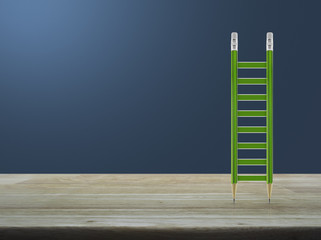 Green pencil ladder on wooden table over light blue gradient background, Business success concept