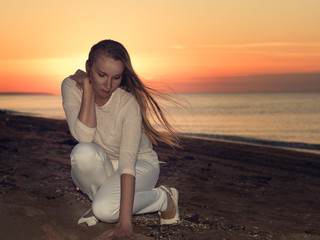 Fototapeta na wymiar Woman in white dress on a sandy beach at sunset.