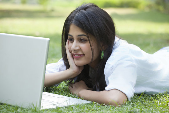 Beautiful young smiling woman using laptop on campus 