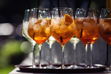 Many glasses with orange cocktails, black background