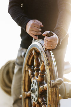 man at the steering wheel of a sailboat
