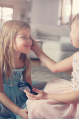 Cute little girls playing with make up in the room.