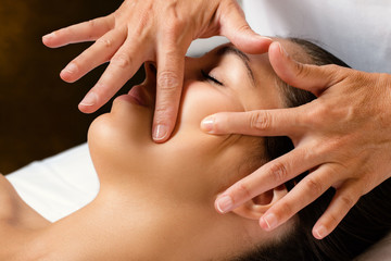 Therapist massaging female cheek.
