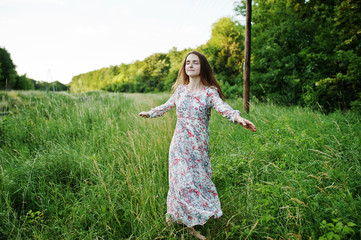 Naklejka na ściany i meble Portrait of a fabulous young woman in dress walking in the tall grass.