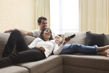 Young couple sitting on sofa watching television