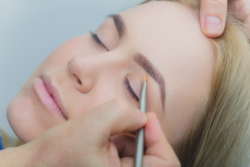 Girl with closed eyes getting makeup on eyelids