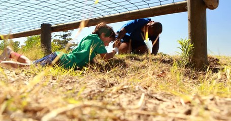 Boy helping his friend during obstacle course - Powered by Adobe