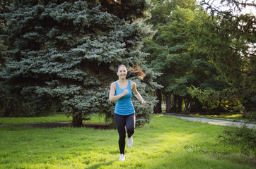 Girl is engaged in fitness in the park, doing exercises. Training on the street in the summer morning. Concept sport healthy lifestyle.