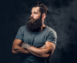Bearded male with tattoos on arms over grey background.