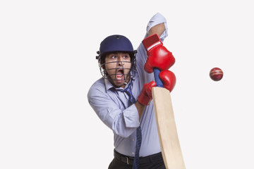 Young businessman hitting ball 