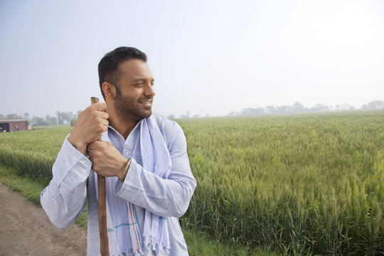 An Indian man looking away while holding a stick 