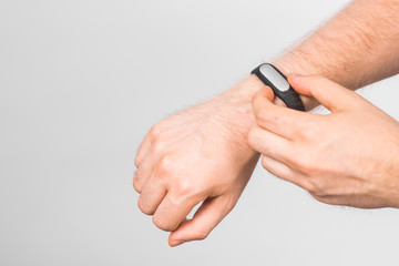 Close-up of man's hand with fitness tracker over grey background