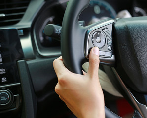 Hand using Car convenient function on steering wheel.