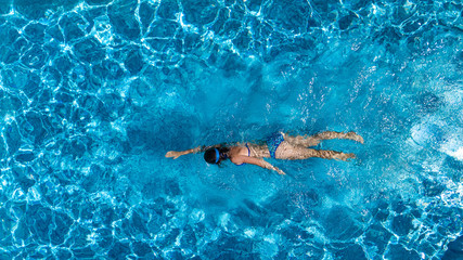 Aerial top view of woman in swimming pool water from above, tropical vacation holaday concept
