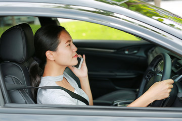 Brunette young woman talking on the phone while driving.