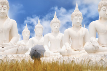 White Buddha statues and woman standing on blue sky background