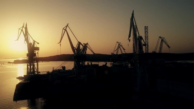 Scenic aerial view of the shipyard cranes and the sea harbour at sunset