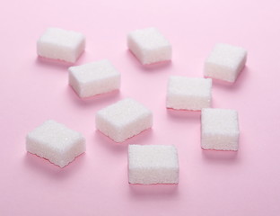 White sugar cubes isolated on pink background and texture