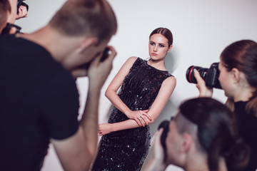 Photographers paparazzi take photos of woman in cocktail dresses.