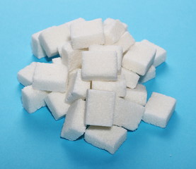 White sugar cubes isolated on blue background and texture