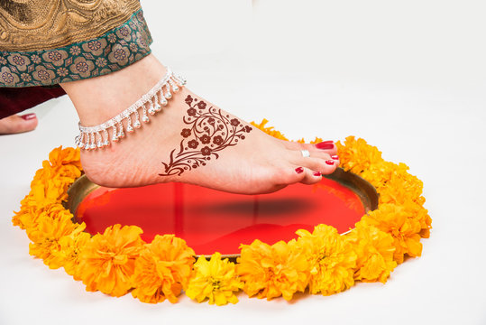 Gruha Pravesh / Gruhapravesh / Griha Pravesh, closeup picture of right feet of a Newly married Indian Hindu bride dipping her fit in a plate filled with liquid kumkum then stepping in husband's house