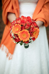 Orange wedding autumn bouquet in the hands of the bride